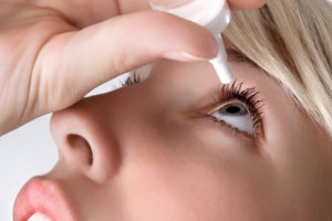 woman applying eyedroppes, close up